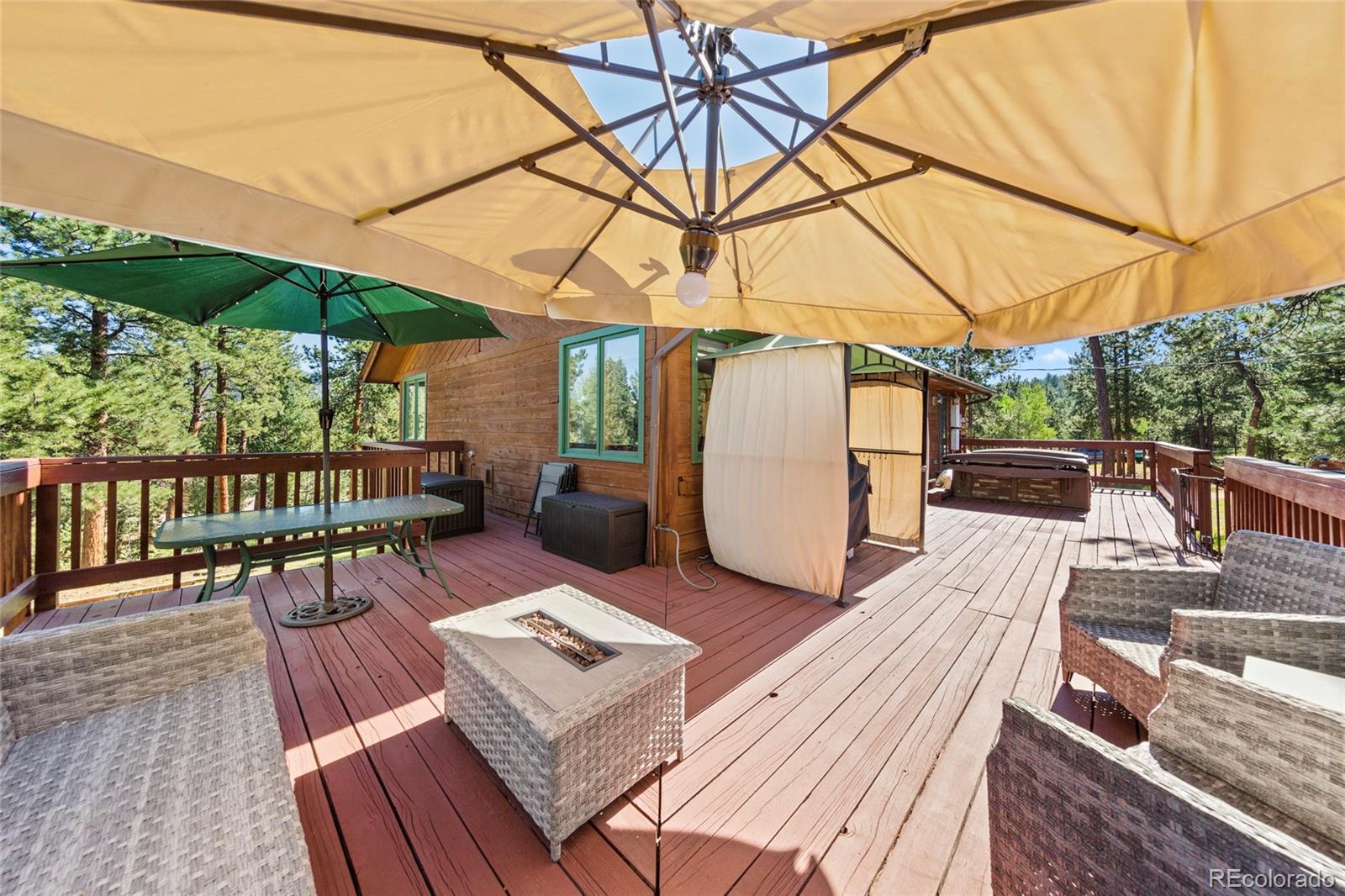 444 Nova Road Pine, CO 80470 - Photo 31 of 40 a view of a patio with table and chairs under an umbrella with wooden floor
