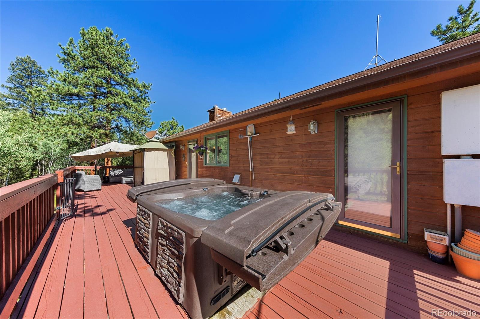 444 Nova Road Pine, CO 80470 - Photo 32 of 40 a terrace of a house with wooden floor outdoor seating and barbeque oven