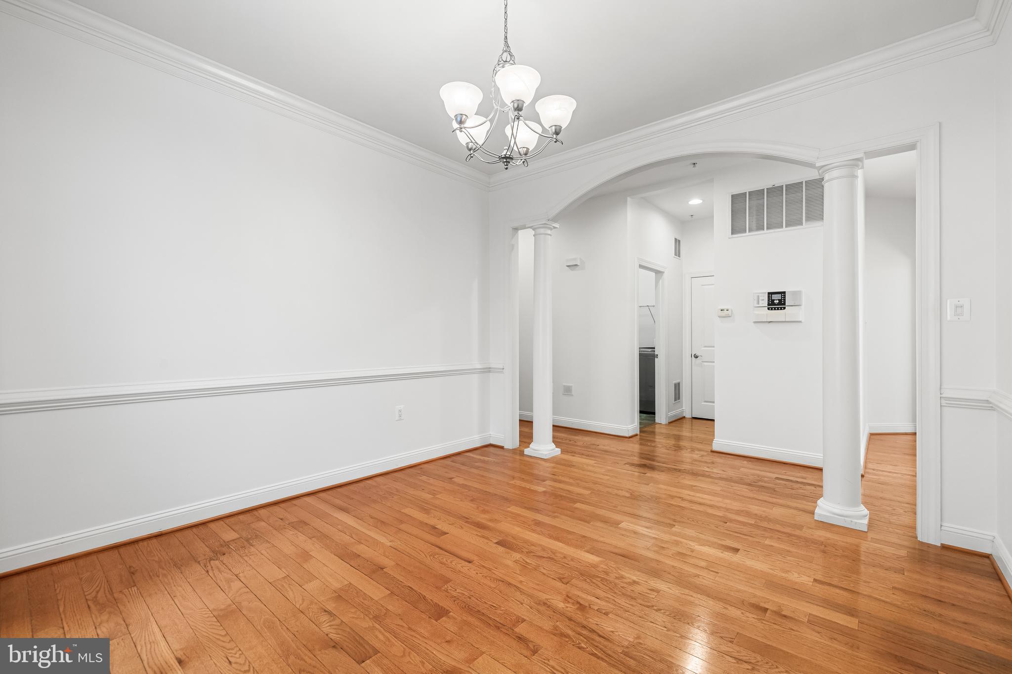 6716 Newstead Lane Baltimore, MD 21209 - Photo 13 of 66 a view of an empty room with wooden floor and a chandelier