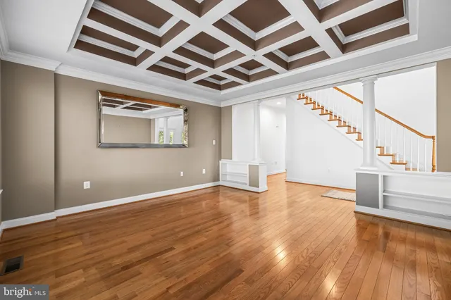 a view of an empty room with wooden floor and a chandelier