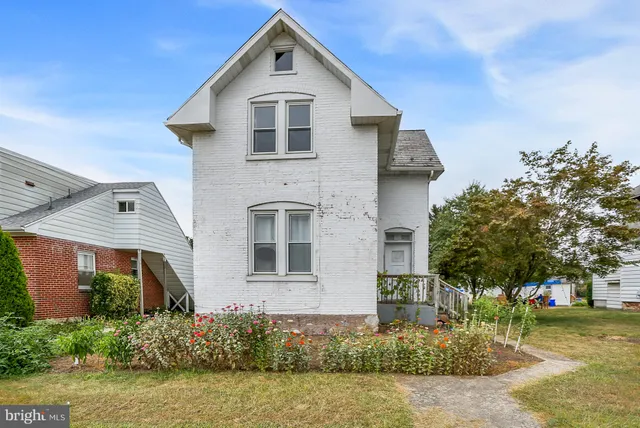 a view of a white house with a big yard and potted plants