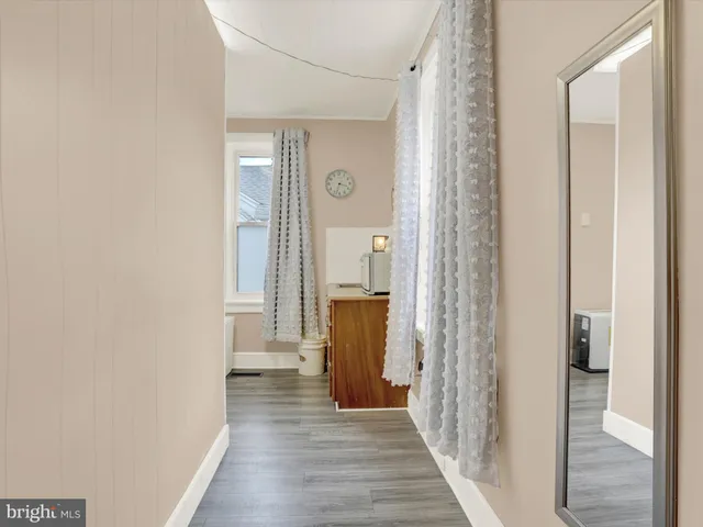 a view of a hallway with wooden floor and a bathroom