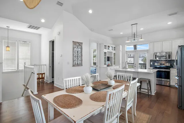 a view of a dining room with furniture a kitchen and chandelier