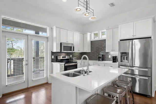 a kitchen with stainless steel appliances granite countertop a refrigerator a sink a stove a dining table and chairs