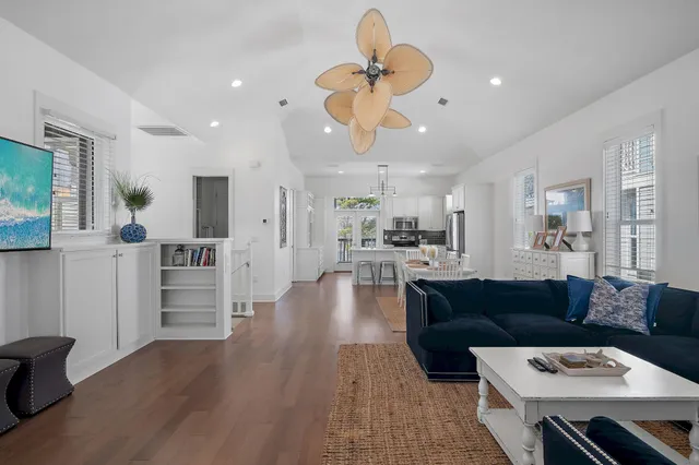 a living room with furniture kitchen view and a wooden floor
