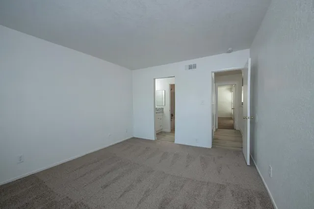 a view of an empty room with closet and mirror