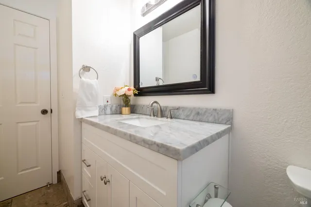 a bathroom with a granite countertop sink and a mirror
