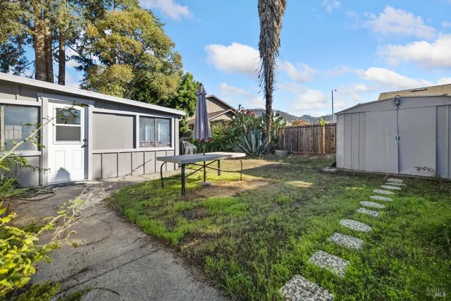 a backyard of a house with table chairs and wooden fence