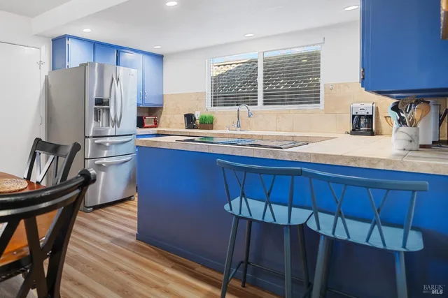 a kitchen with stainless steel appliances a refrigerator a sink a stove a table and chairs