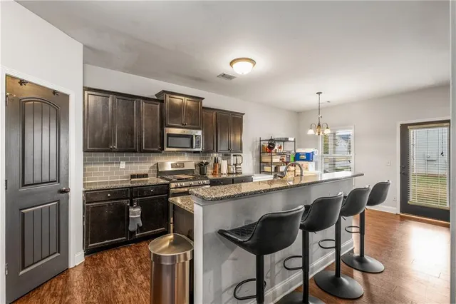 a kitchen with stainless steel appliances granite countertop a stove top oven a sink refrigerator and cabinets