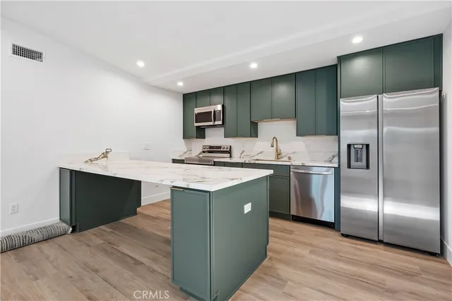 a kitchen with kitchen island a sink stainless steel appliances and cabinets