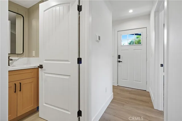 a view of a hallway with wooden floor and a bathroom