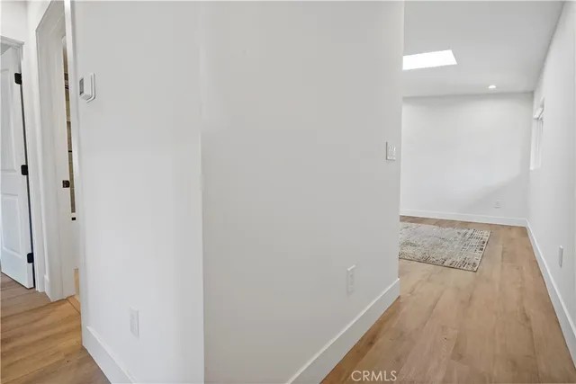 a view of a hallway to room with wooden floor and cabinet