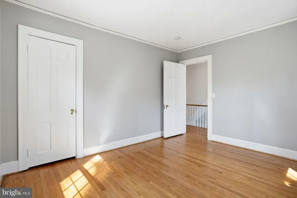a view of an empty room with wooden floor and closet