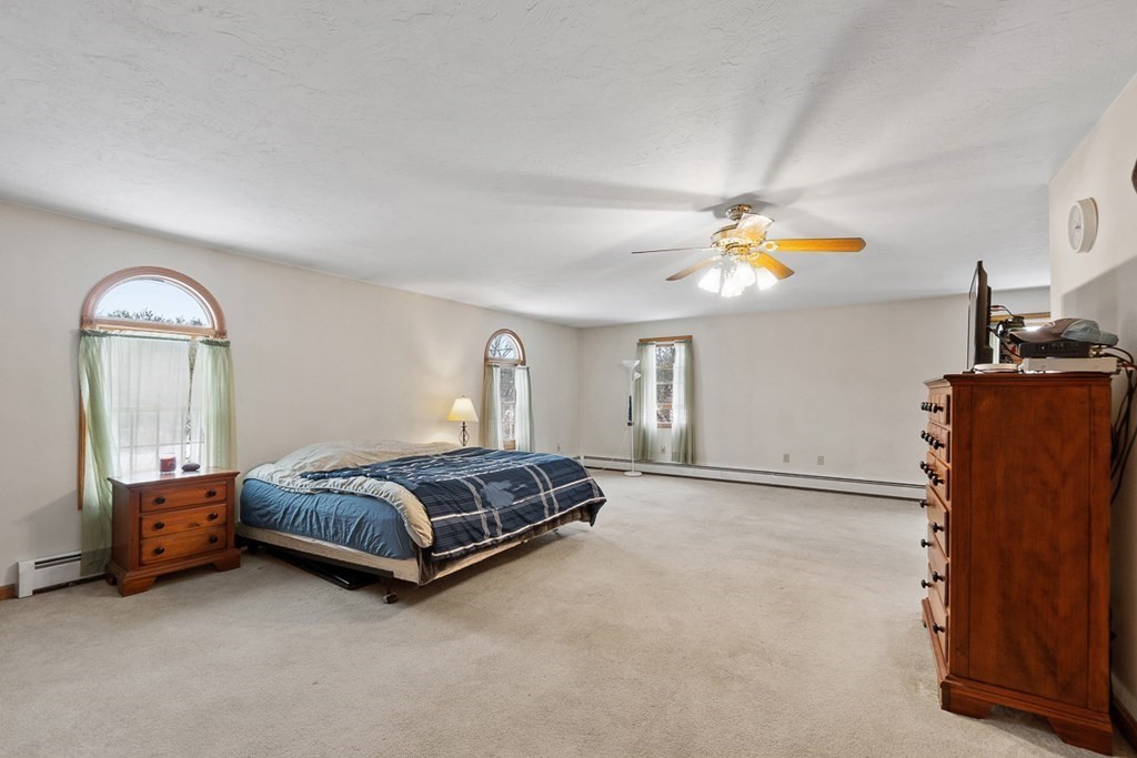 164 Sterling Road Princeton, MA 01541 - Photo 18 of 36 a spacious bedroom with a bed and a chandelier