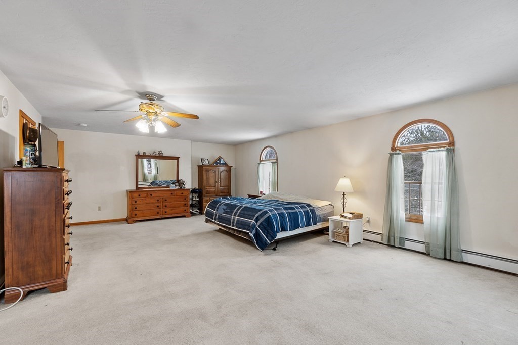 164 Sterling Road Princeton, MA 01541 - Photo 20 of 36 a spacious bedroom with a bed and a chandelier