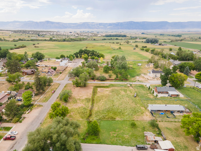 74 West Ctr Spring Spring City, UT 84662 - Photo 5 of 15 Expansive land parcel featuring a partially cleared building site, existing residential structures, mature trees, and agricultural fields in the distance