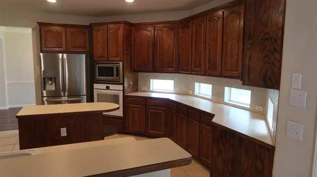 a kitchen with stainless steel appliances wooden cabinets a sink and a refrigerator
