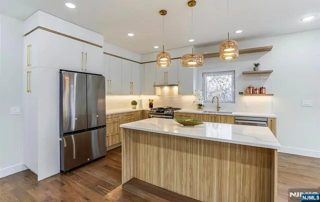 a large kitchen with stainless steel appliances kitchen island granite countertop a refrigerator and a sink