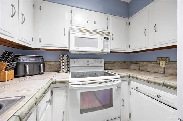 a kitchen with granite countertop white cabinets and white appliances