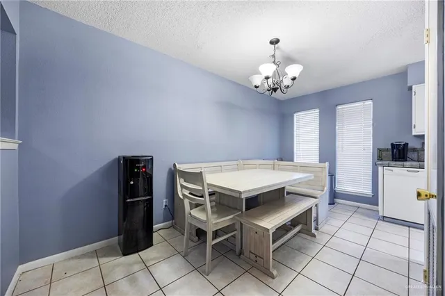 a dining room with a chandelier and kitchen view