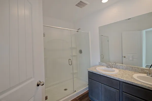 a bathroom with a granite countertop sink a mirror and shower