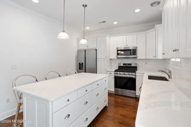 a kitchen with stainless steel appliances a stove a sink a refrigerator a stove a microwave and a refrigerator