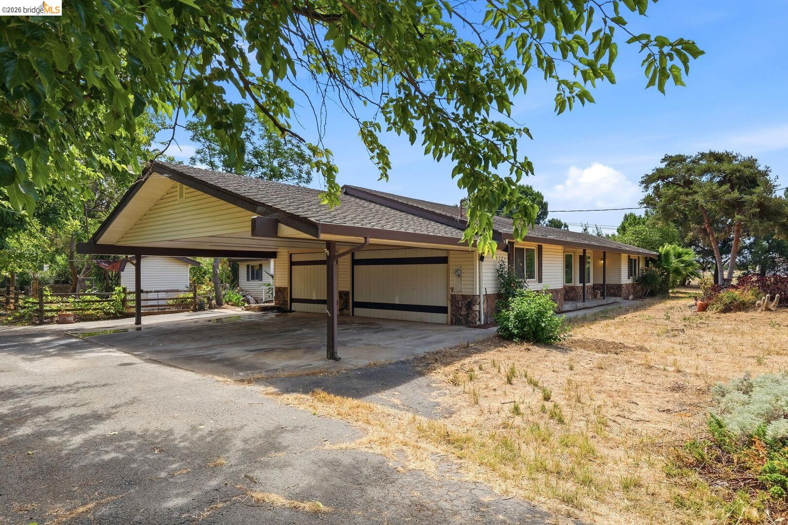 Exterior showcasing a carport with a covered driveway, a horizontal siding facade with stone accents, a covered front porch, and a brown shingle roof