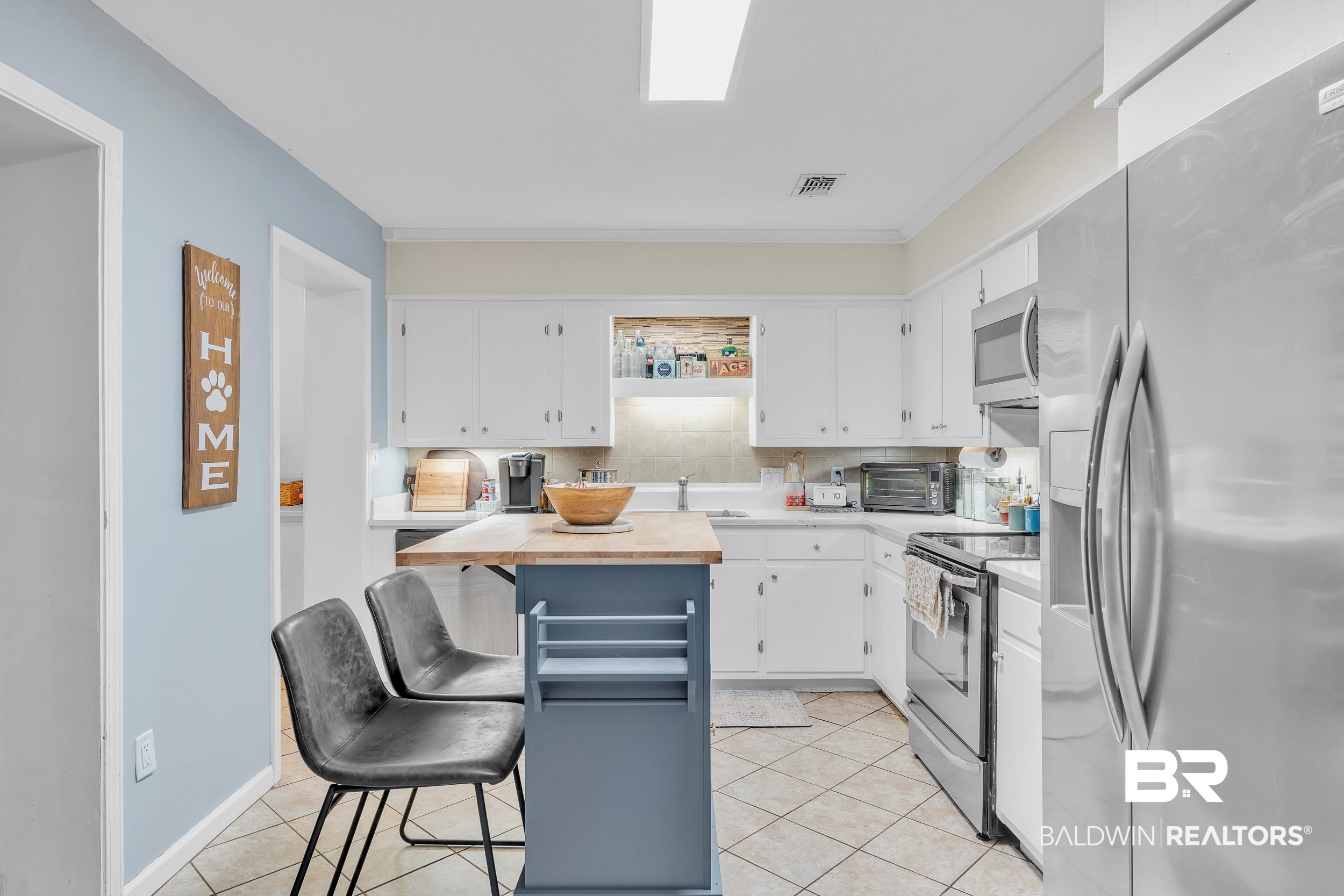 206 West Jackson Avenue Summerdale, AL 36580 - Photo 15 of 37 Kitchen featuring stainless steel appliances, white cabinets, a kitchen breakfast bar, light tile patterned flooring, and crown molding