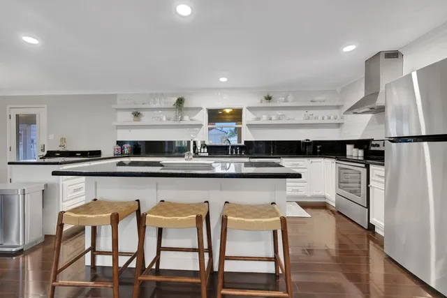 a kitchen with stainless steel appliances granite countertop a table chairs sink and cabinets