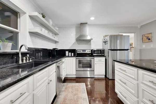 a kitchen with granite countertop a sink and stainless steel appliances