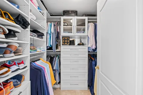 a view of walk in closet with clothes and shoes