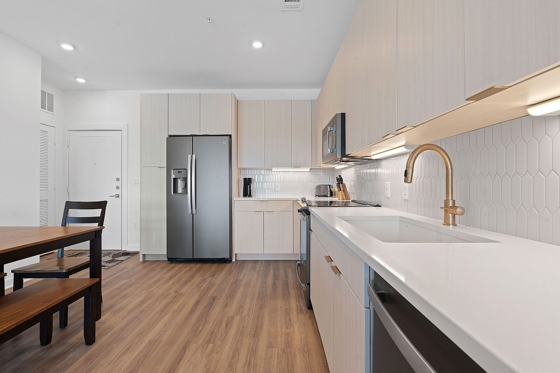 4802 South Congress Avenue, Unit 418 Austin, TX 78745 - Photo 17 of 24 a kitchen with a sink a refrigerator and wooden floor