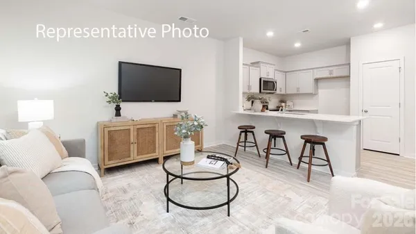 a living room with furniture a flat screen tv and kitchen view