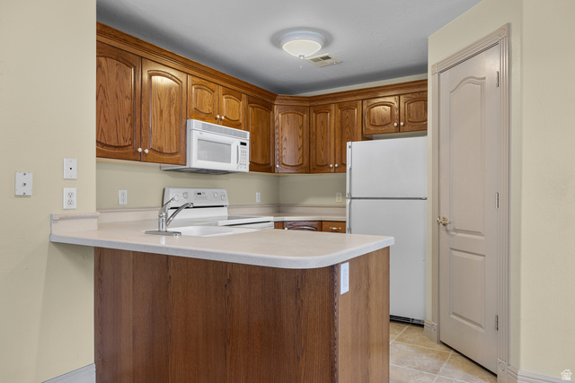 389 North Main Street St. George, UT 84770 - Photo 30 of 44 Kitchen with white appliances, wood finish cabinets, light countertops, a peninsula, and light tile patterned flooring
