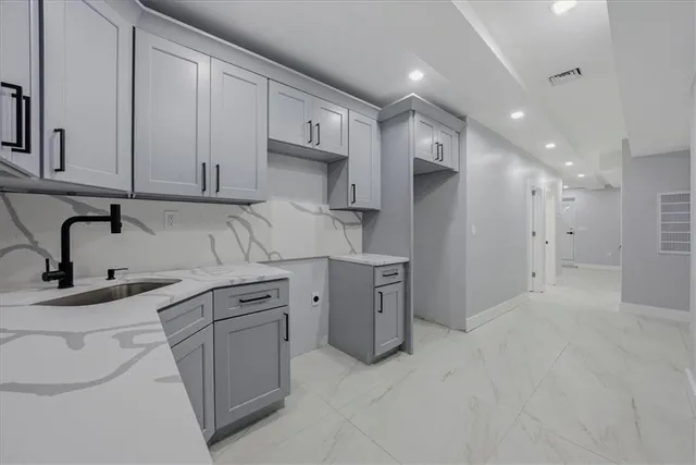 a kitchen with white cabinets and sink