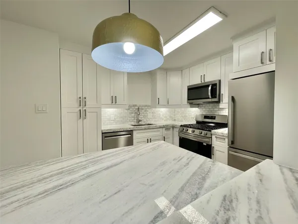 a kitchen with stainless steel appliances a stove refrigerator and microwave