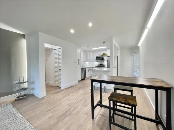 a kitchen with stainless steel appliances granite countertop a table chairs sink and cabinets