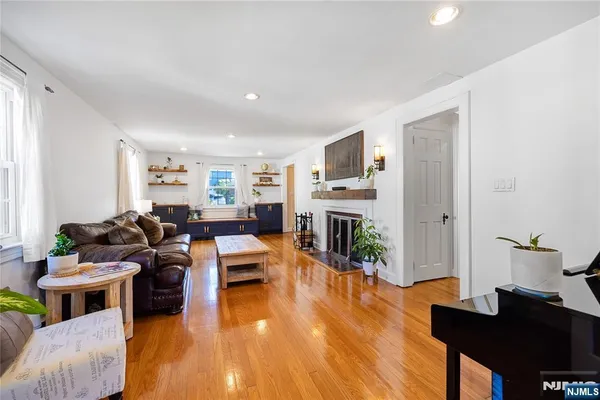 a view of a hallway with wooden floor staircase and a living room