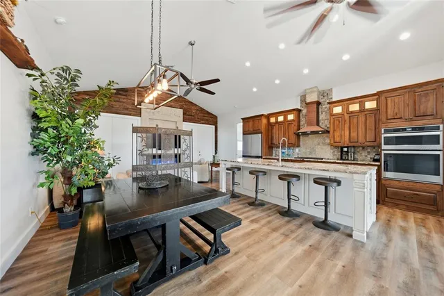 a kitchen with stainless steel appliances kitchen island granite countertop a stove a refrigerator and a dining table with wooden floor