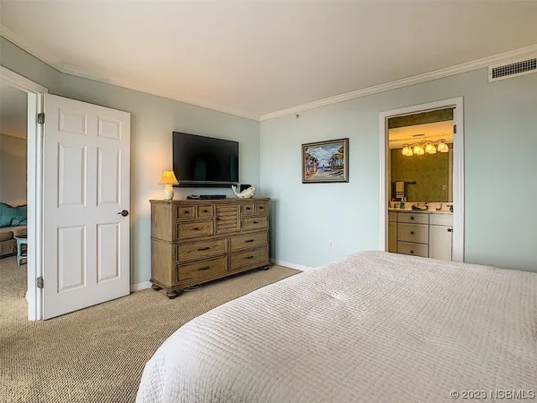 a large bedroom with a bed and flat screen tv
