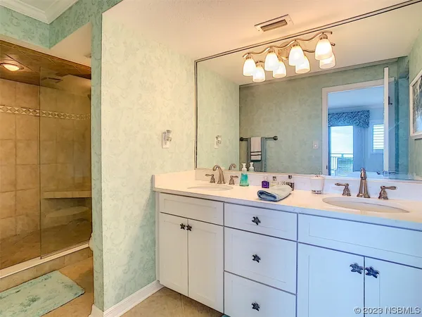 a bathroom with a double vanity sink mirror and next to a shower