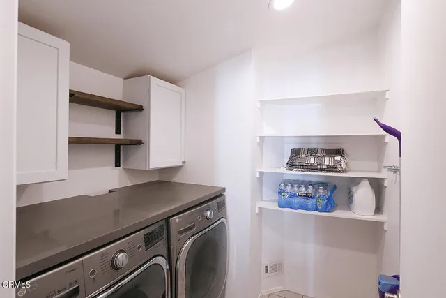 a view of washer and dryer with wooden cabinets