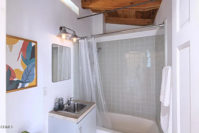 a bathroom with a sink a mirror a bathtub and shower