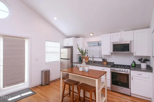 a kitchen with kitchen island a stove a table and chairs in it