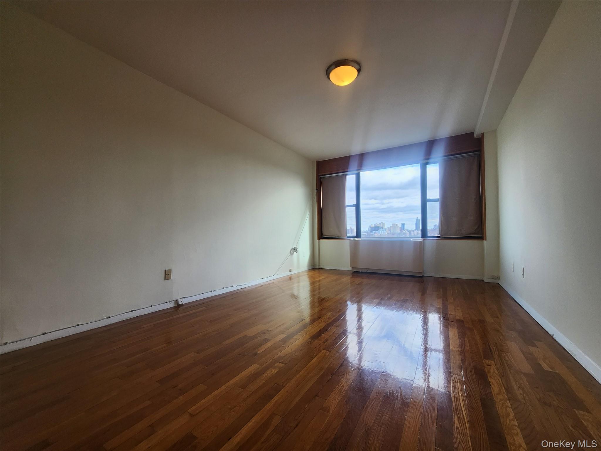 87-14 57th Road, Unit PHA Queens, NY 11373 - Photo 5 of 15 an empty room with wooden floor and windows