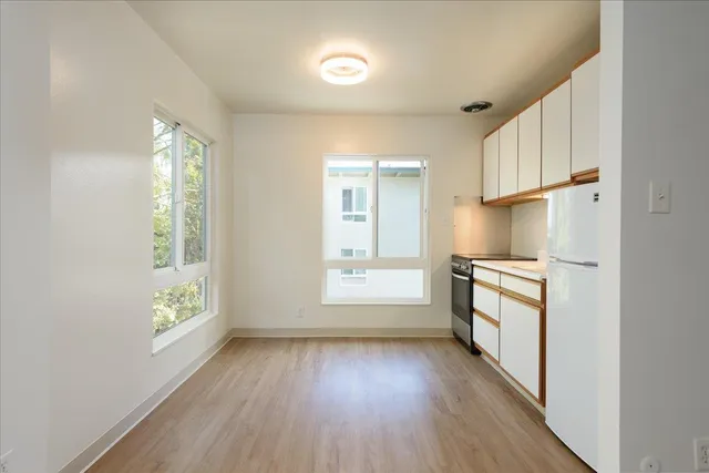 a kitchen with cabinets wooden floor and a window