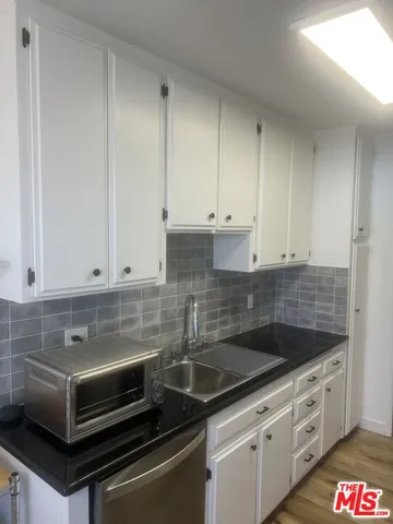 a kitchen with granite countertop white cabinets and sink