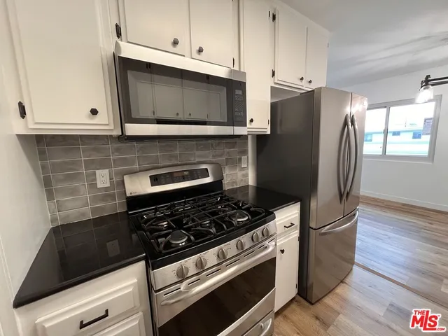 a kitchen with granite countertop a refrigerator stove and microwave