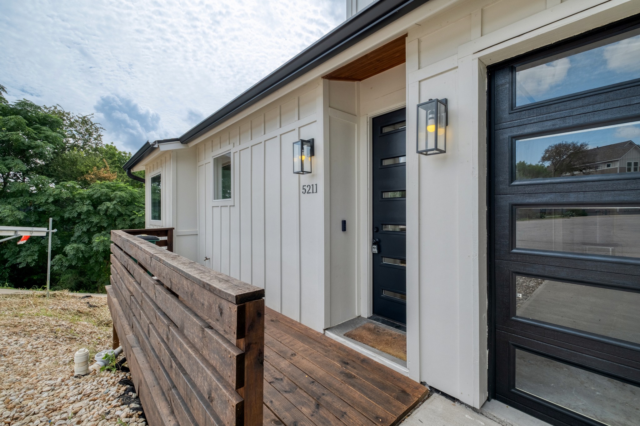 5211 Rob-Scott Street Austin, TX 78721 - Photo 2 of 24 A modern facade with crisp white siding, contrasting black door and garage, and a warm wooden entry.